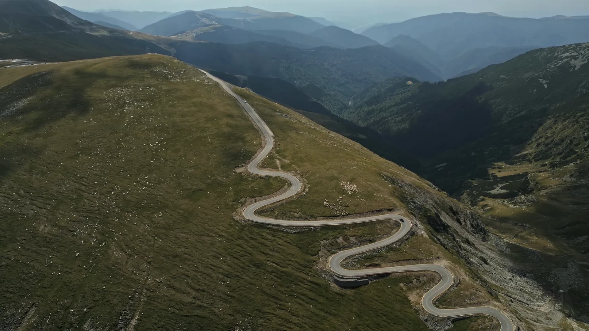 A paved mountain road winding up a green ridge