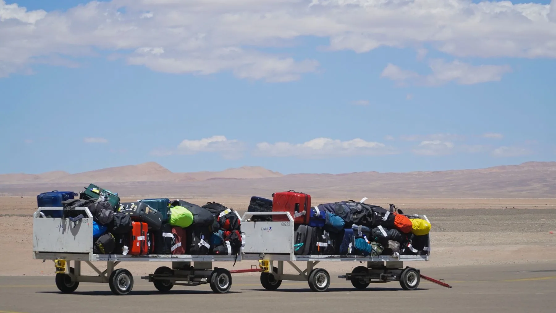 Baggage carts stacked with checked luggage on an airport tarmac