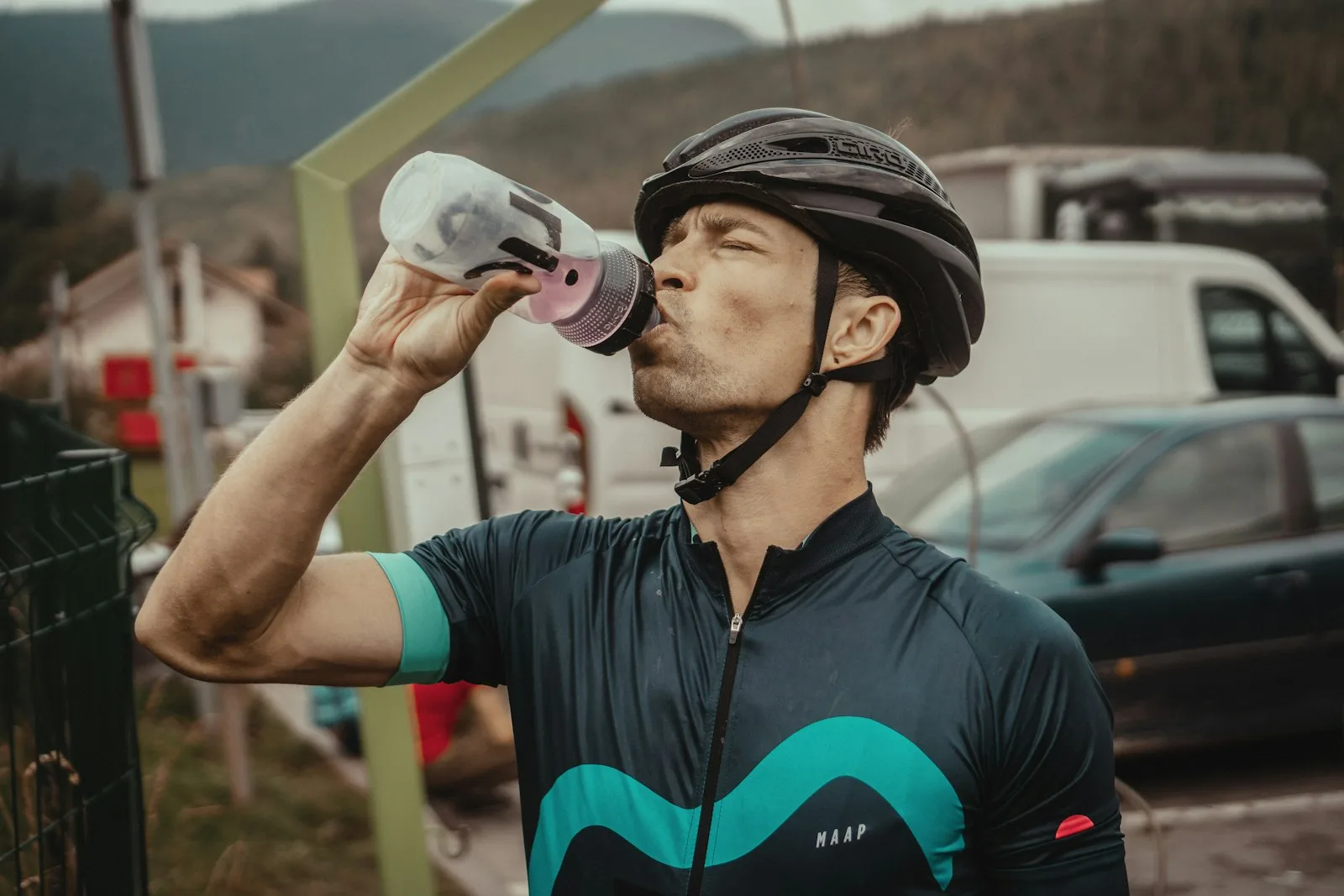 Cyclist in a helmet drinking from a water bottle