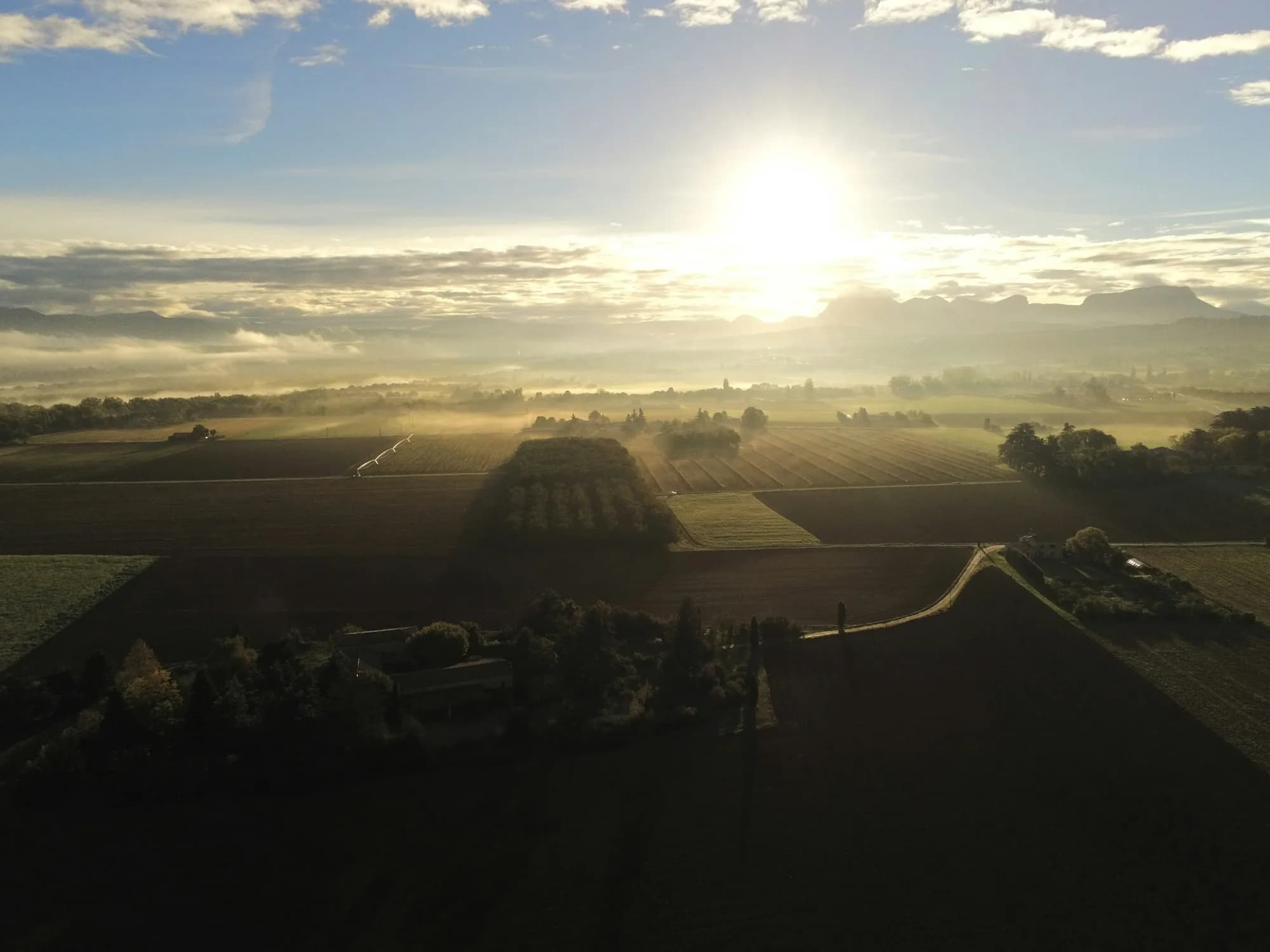 Sunrise over misty farmland seen from above, the quiet early hours before a ride