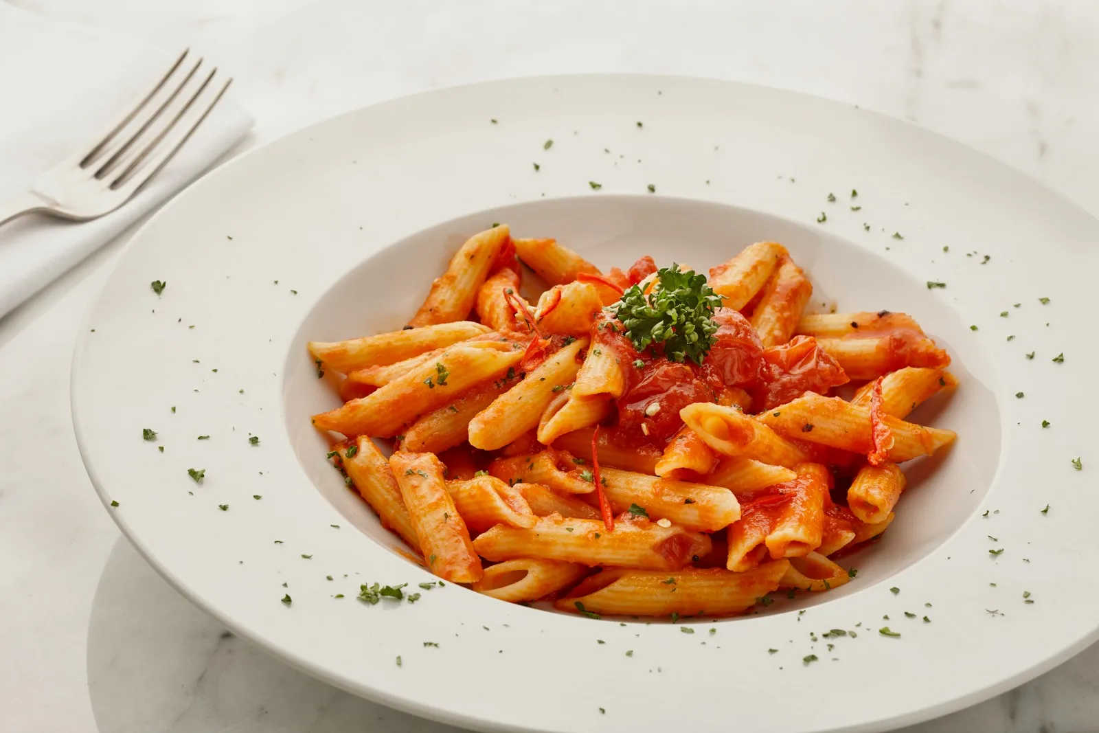 A plate of penne pasta in tomato sauce on a table, the carbohydrate-heavy dinner that refills your legs after a long bike ride