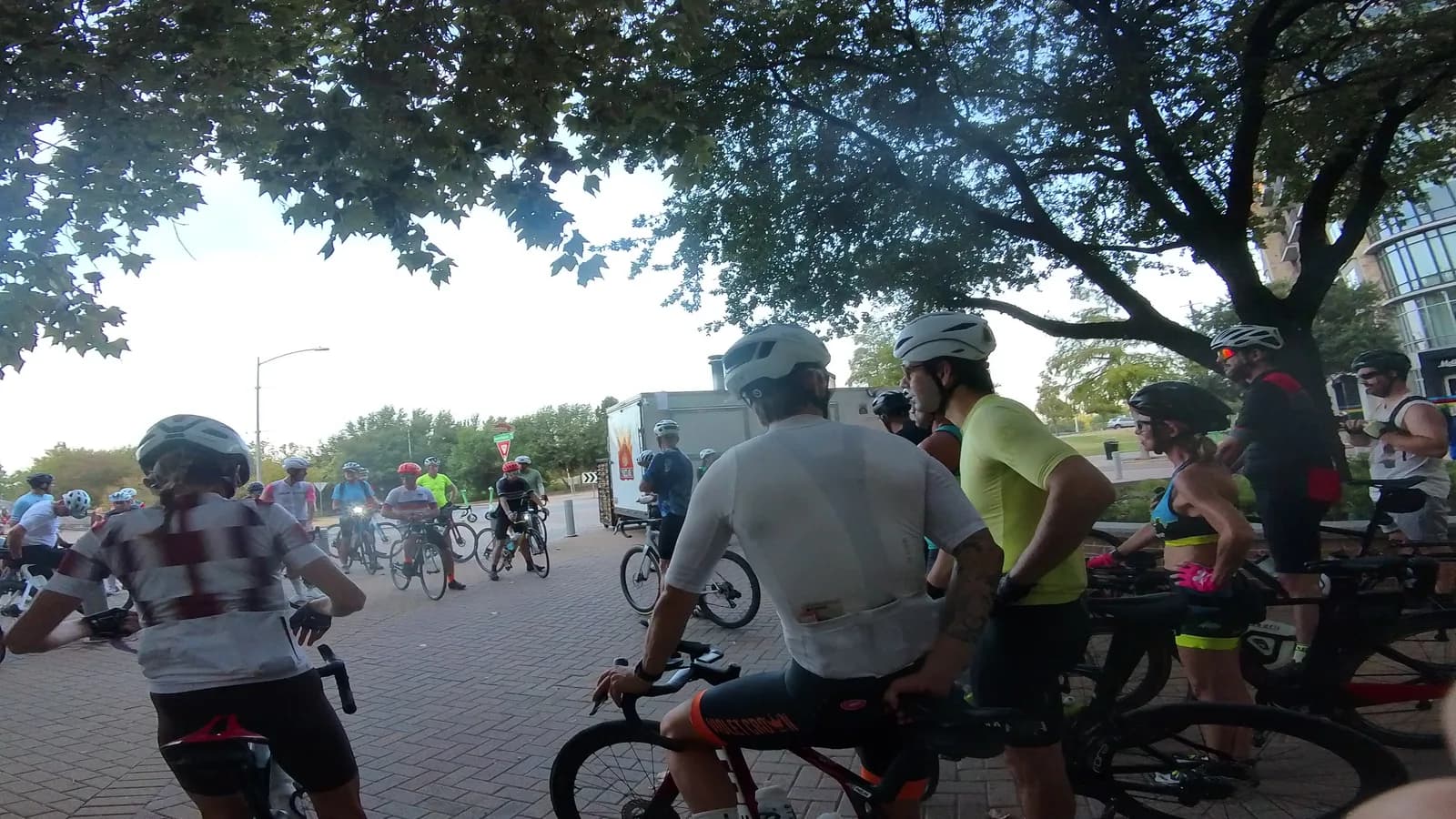 Riders gathering under a tree on the plaza before the ride