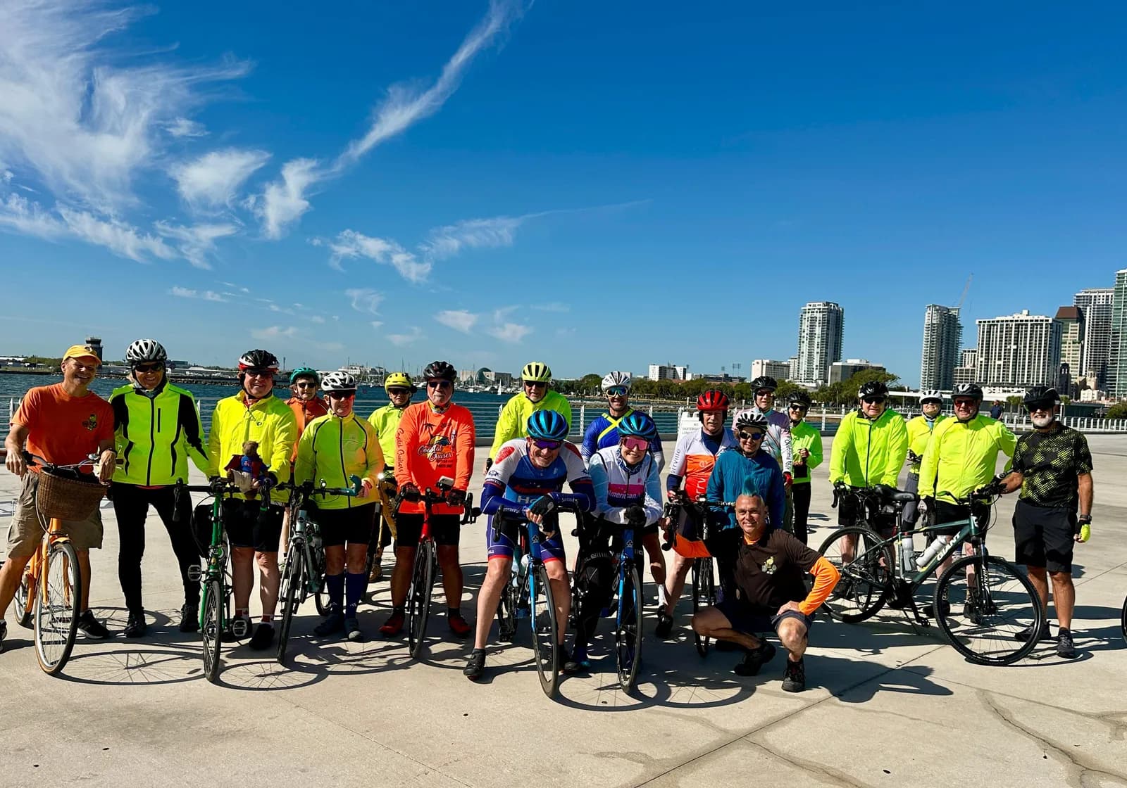 Group photo on the waterfront before a morning ride, everyone in high-vis and smiling