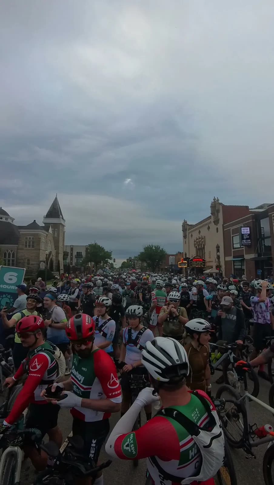 A packed mass start on a small-town main street, hundreds of riders waiting for the flag