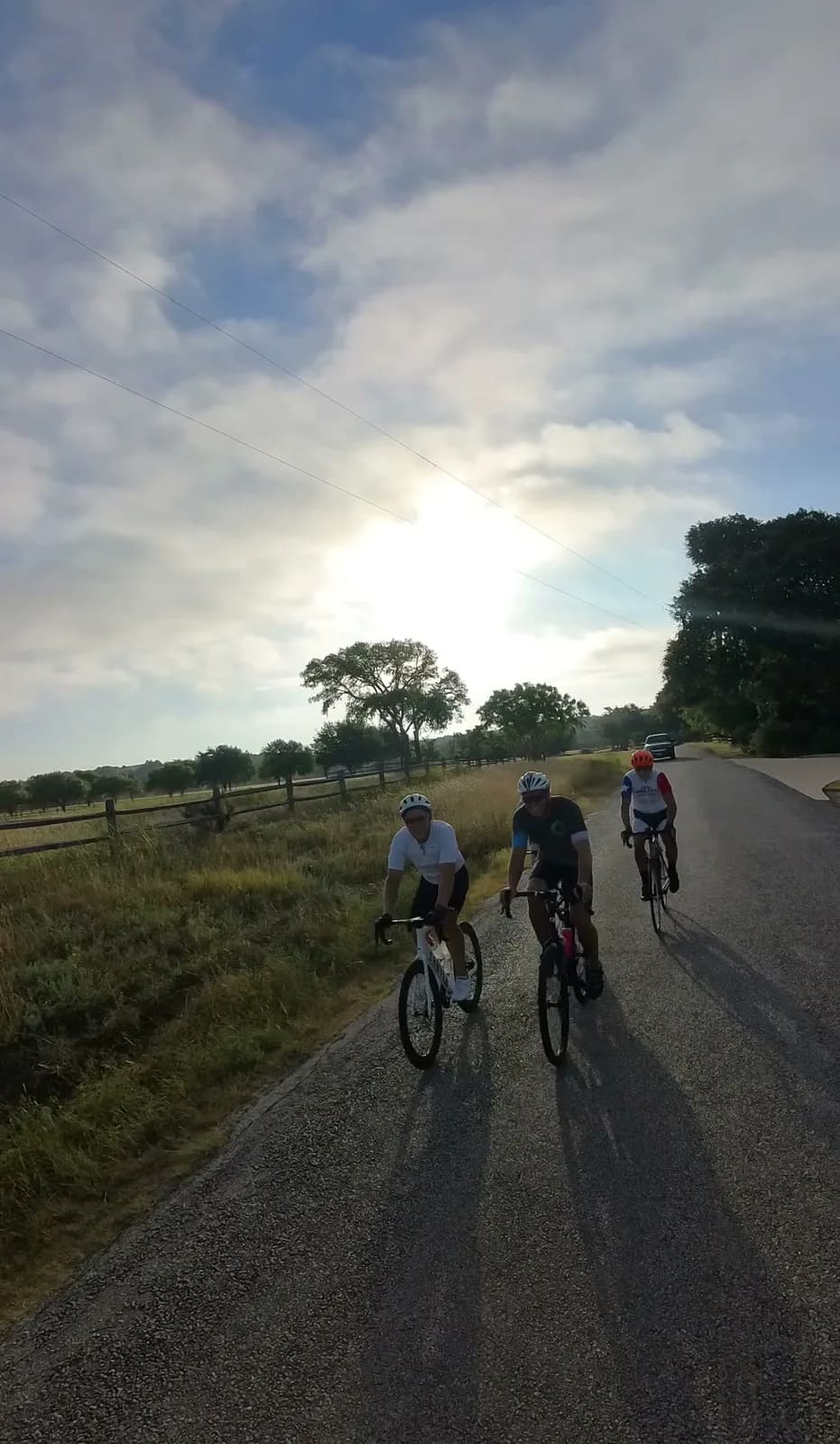 Three riders side by side on a Hill Country road at golden hour