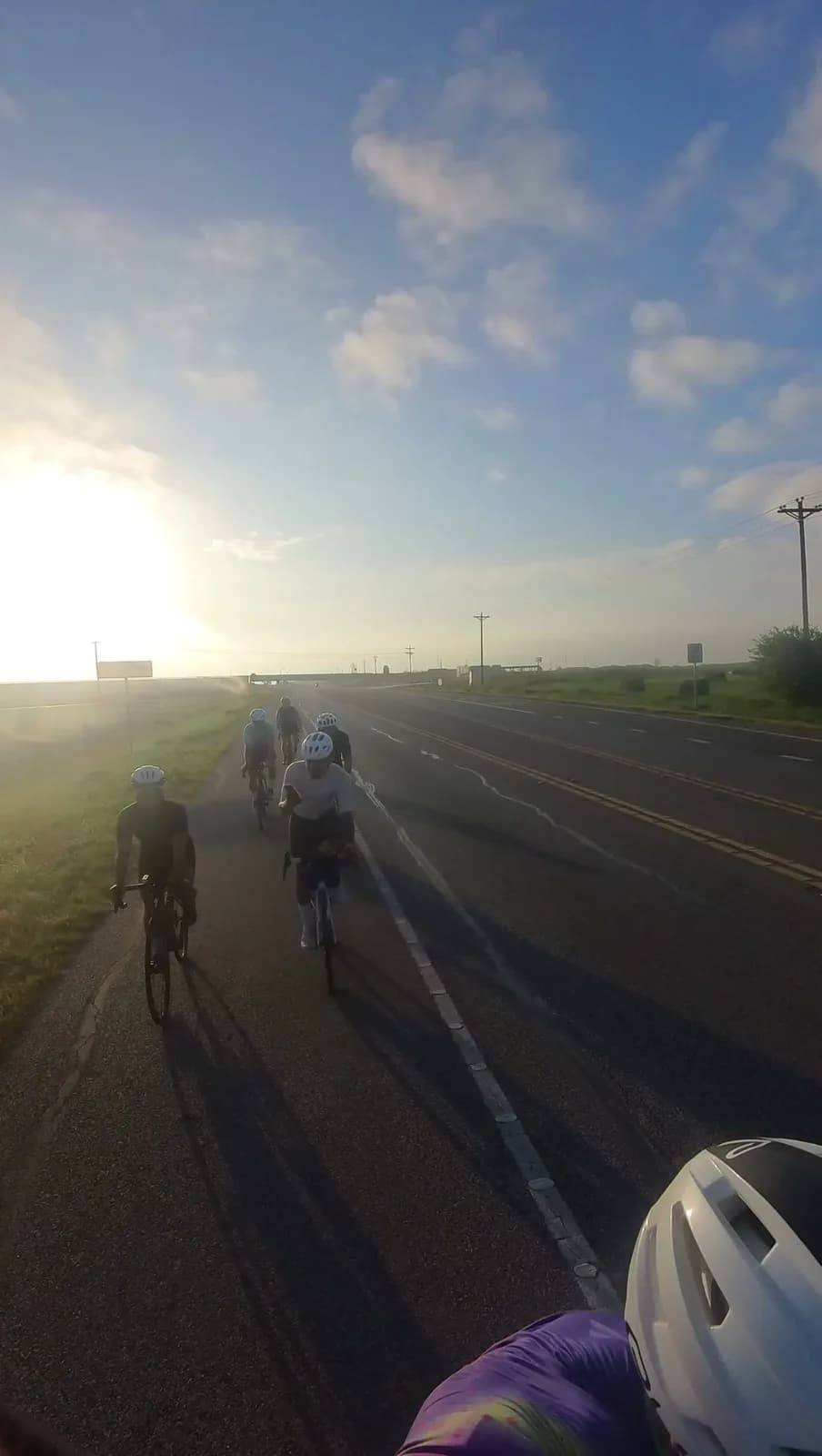 A paceline into the sunrise on a straight country road