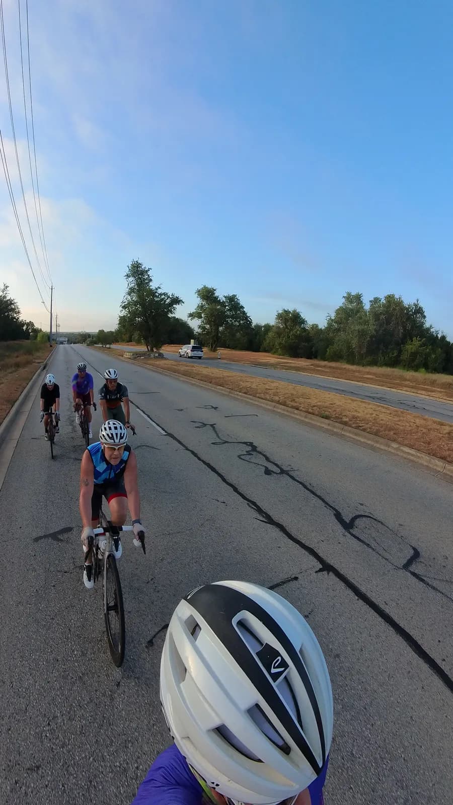 The paceline strung out on an open country road under a clear sky