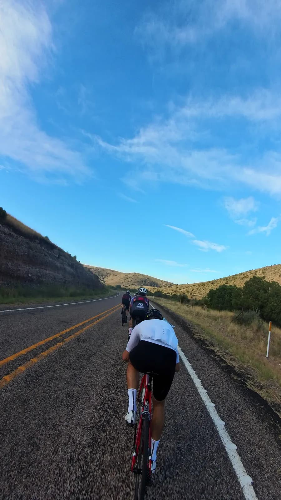 The group climbing a desert highway, hills rising on both sides