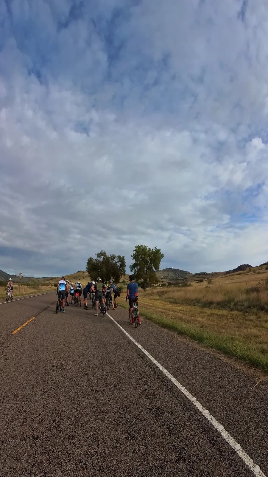 The group rolling out along a prairie road under a wide sky