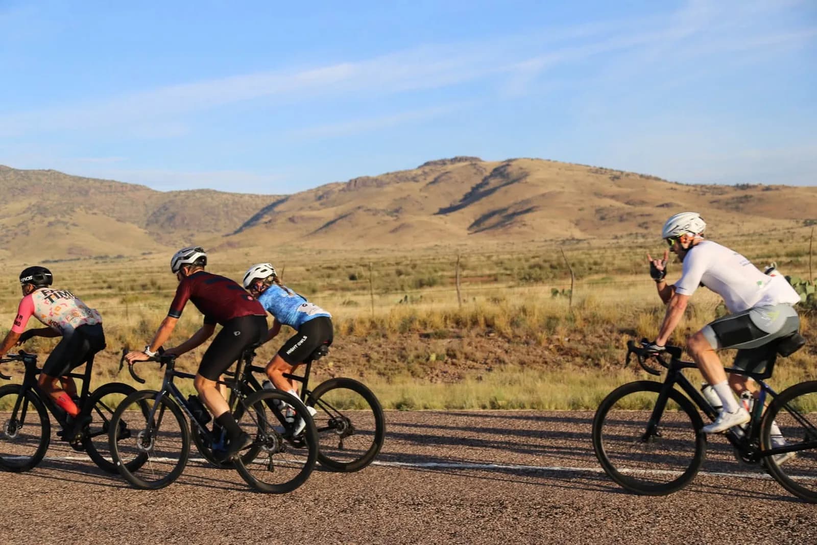 Riders passing below bare desert hills on a bright morning