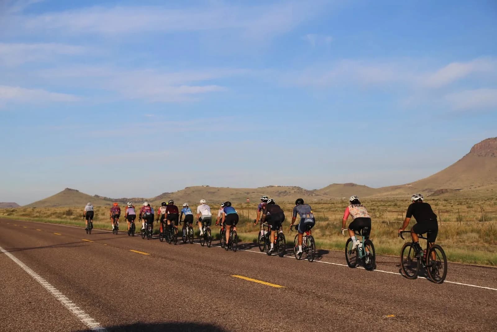 A long paceline strung along a desert highway, the whole group in one line