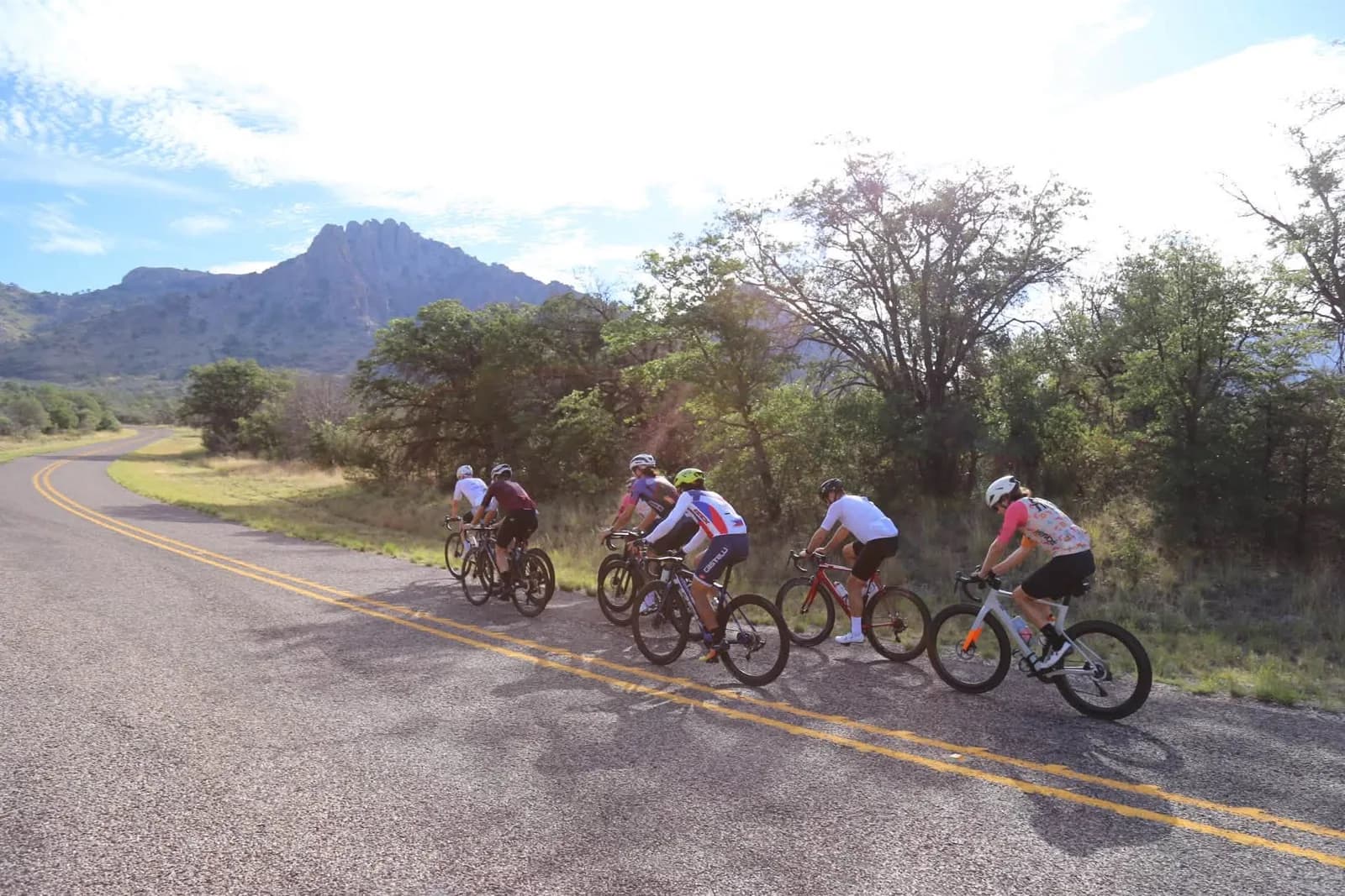 Riders leaning into a bend with a rocky peak behind