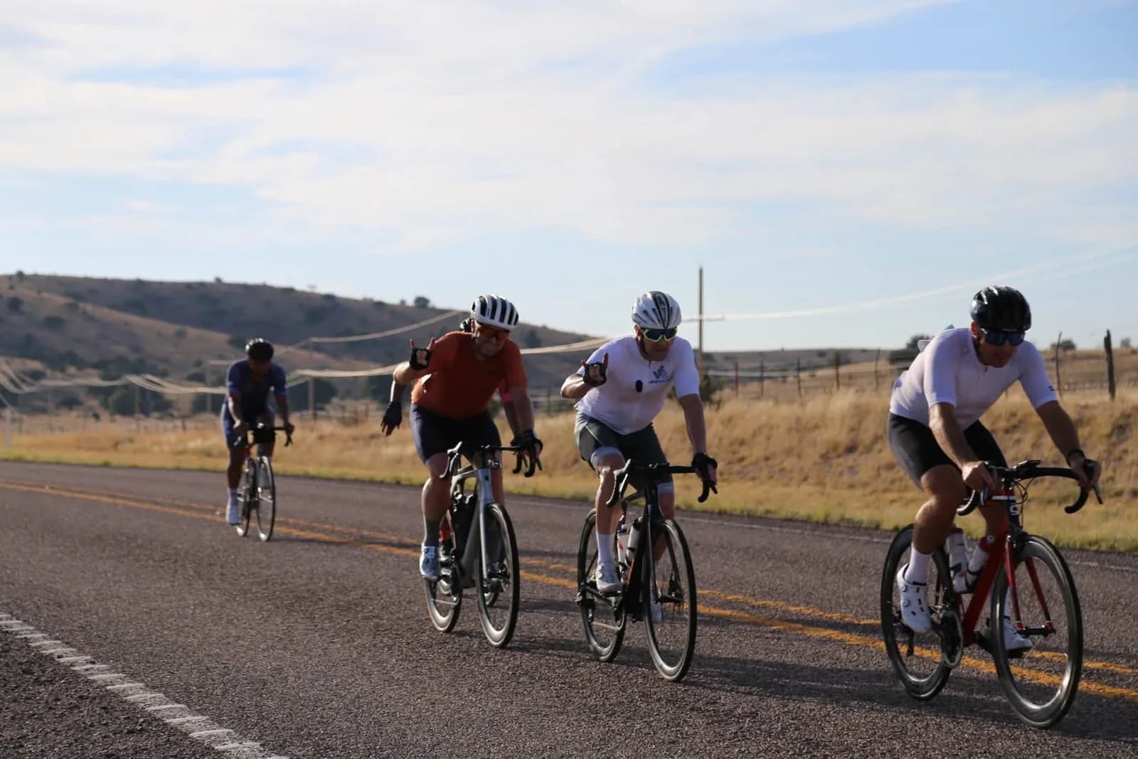Four riders abreast on a ranch highway, grassland to the horizon