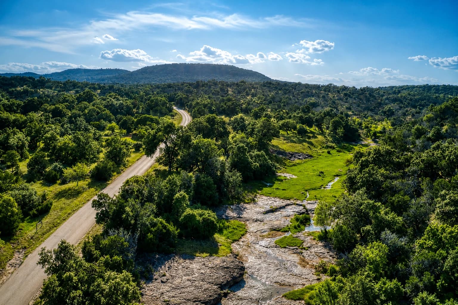 Aerial view of a Hill Country road winding alongside a creek